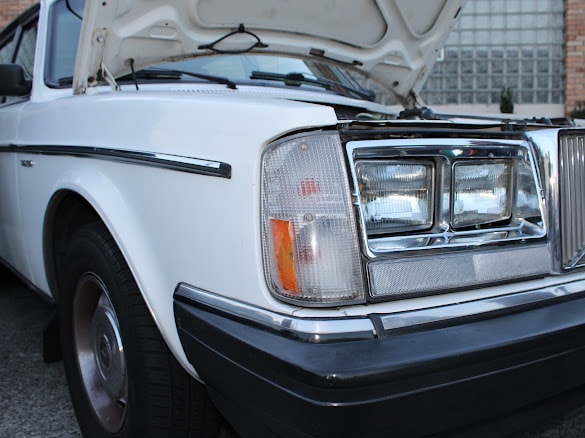 Vintage white Volvo hood open, headlight detail
