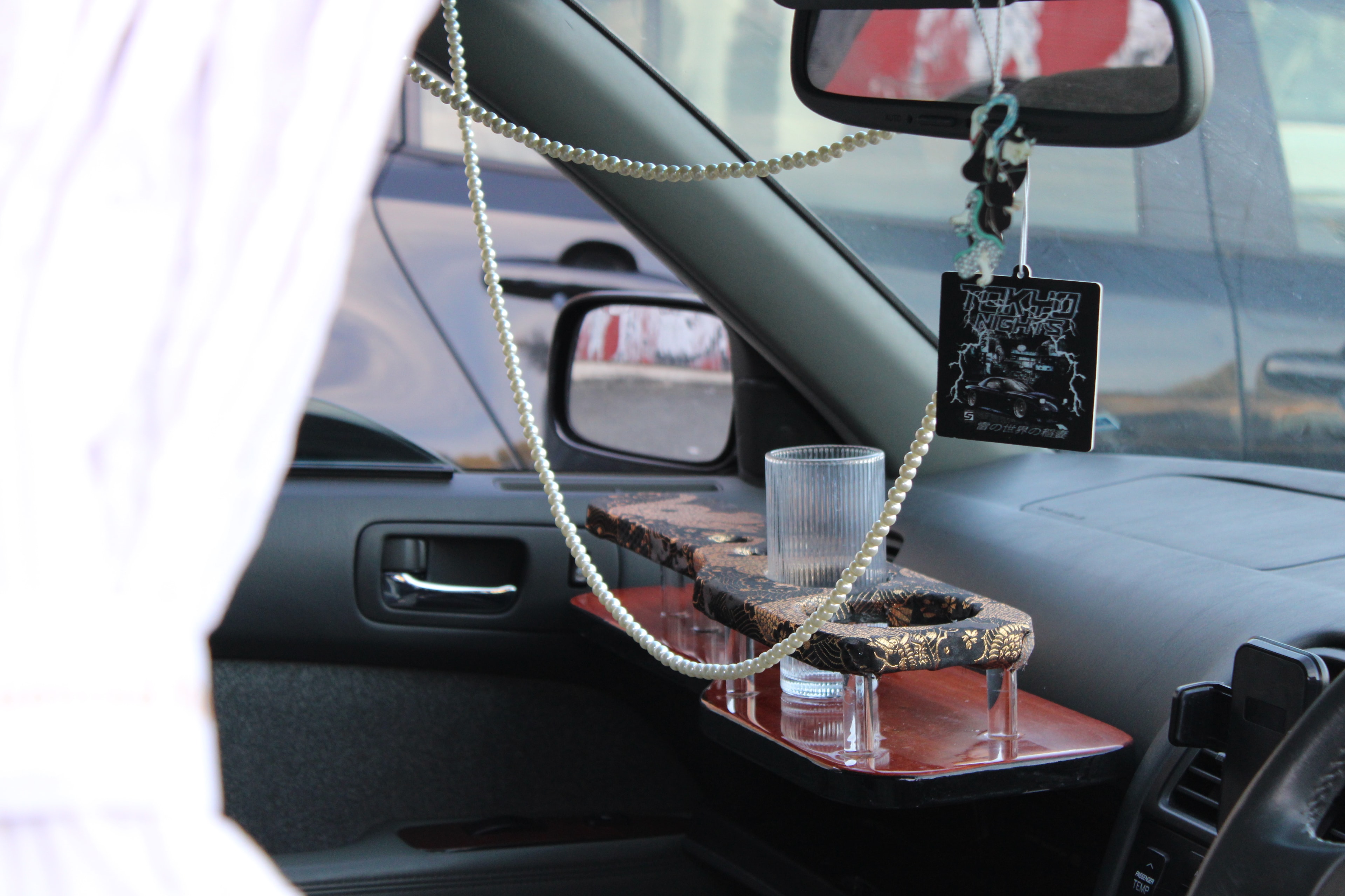 Car interior with pearl bead necklace and Tokyo Nights charm